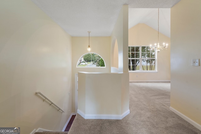 hallway featuring carpet floors, a chandelier, a textured ceiling, and high vaulted ceiling