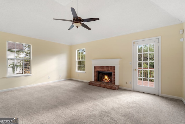 unfurnished living room with a wealth of natural light, light carpet, a brick fireplace, and ceiling fan