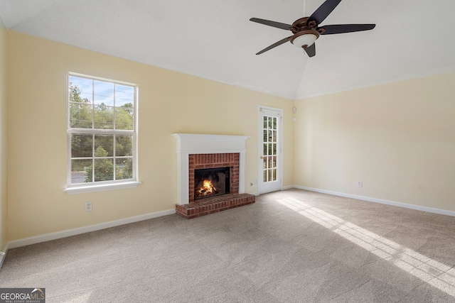 unfurnished living room featuring lofted ceiling, a brick fireplace, carpet flooring, and ceiling fan