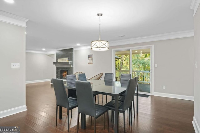 dining space with crown molding, a tile fireplace, and dark hardwood / wood-style floors