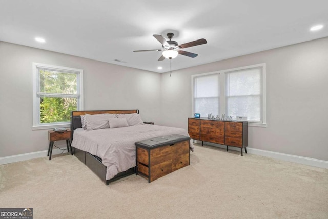 bedroom featuring ceiling fan, multiple windows, and light colored carpet