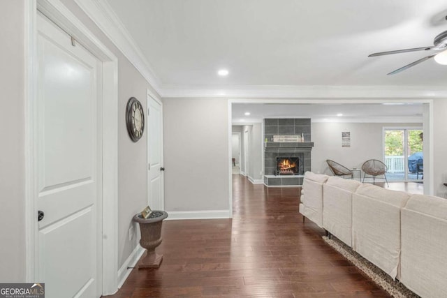 living room with crown molding, ceiling fan, a fireplace, and dark hardwood / wood-style flooring