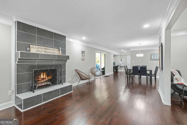 living room featuring ornamental molding, hardwood / wood-style floors, and a tiled fireplace