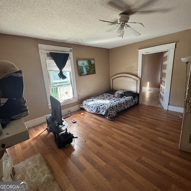 bedroom featuring ceiling fan, hardwood / wood-style flooring, and a textured ceiling