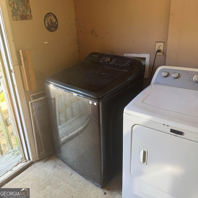 laundry area with washing machine and dryer and light tile patterned floors