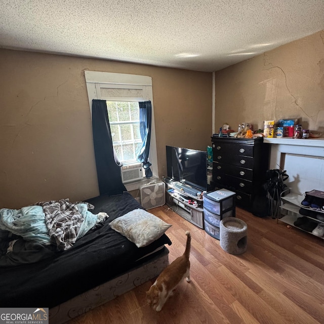 bedroom with a textured ceiling, cooling unit, and hardwood / wood-style flooring