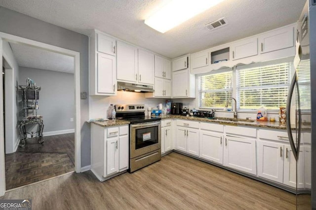 kitchen featuring appliances with stainless steel finishes, light hardwood / wood-style flooring, and white cabinetry