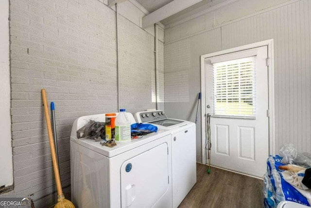 clothes washing area with brick wall, dark hardwood / wood-style floors, and separate washer and dryer