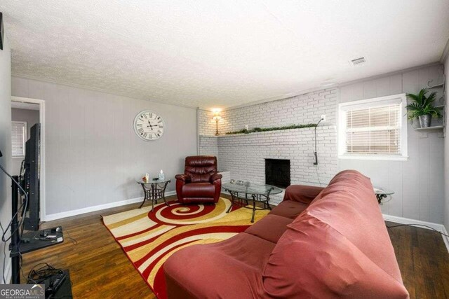 living room with a fireplace, a textured ceiling, and dark hardwood / wood-style floors