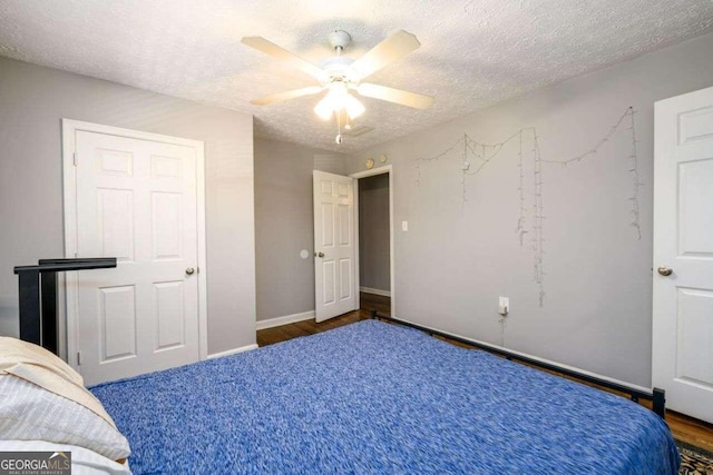 unfurnished bedroom featuring dark wood-type flooring, a textured ceiling, and ceiling fan