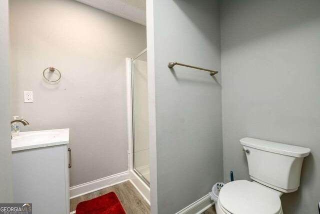 bathroom featuring vanity, an enclosed shower, toilet, and wood-type flooring