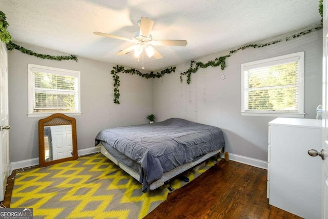 bedroom with a textured ceiling, dark wood-type flooring, and ceiling fan