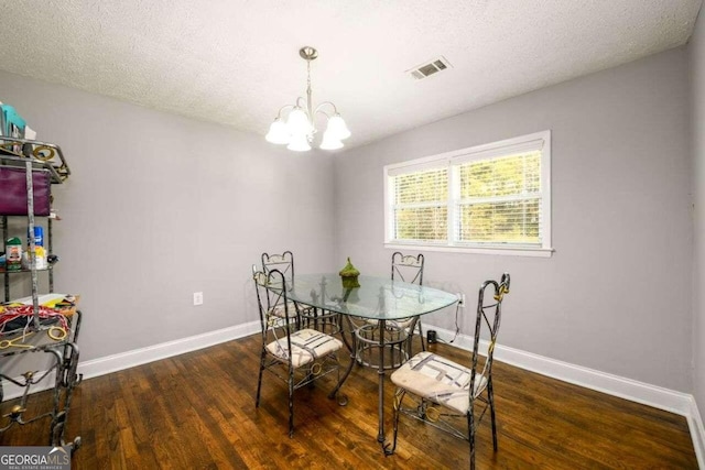 dining area with a textured ceiling, a chandelier, and dark hardwood / wood-style floors