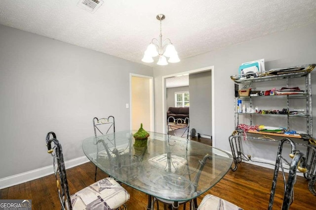 dining room with dark wood-type flooring, a notable chandelier, and a textured ceiling