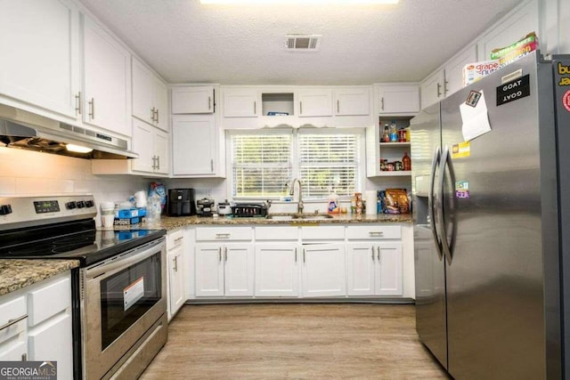 kitchen featuring stone countertops, white cabinetry, stainless steel appliances, and light wood-type flooring