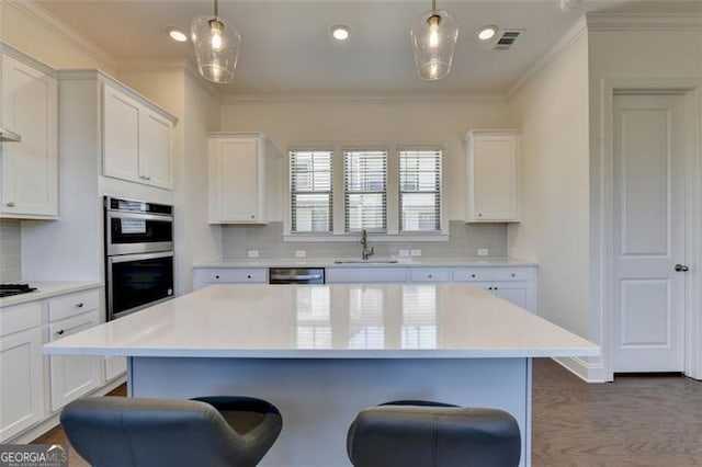 kitchen featuring white cabinets, pendant lighting, and appliances with stainless steel finishes