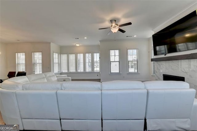 living room with a fireplace, ceiling fan, and ornamental molding