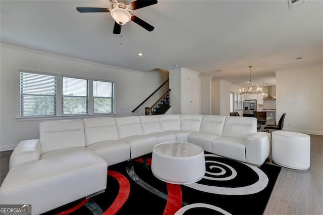 living room featuring hardwood / wood-style floors, ceiling fan with notable chandelier, and ornamental molding