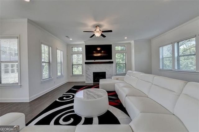 living room with hardwood / wood-style floors, ceiling fan, crown molding, and a premium fireplace