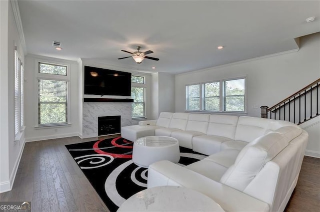 living room featuring crown molding, a high end fireplace, dark hardwood / wood-style floors, and ceiling fan