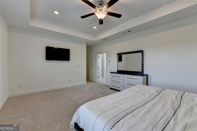 carpeted bedroom with ceiling fan and a tray ceiling