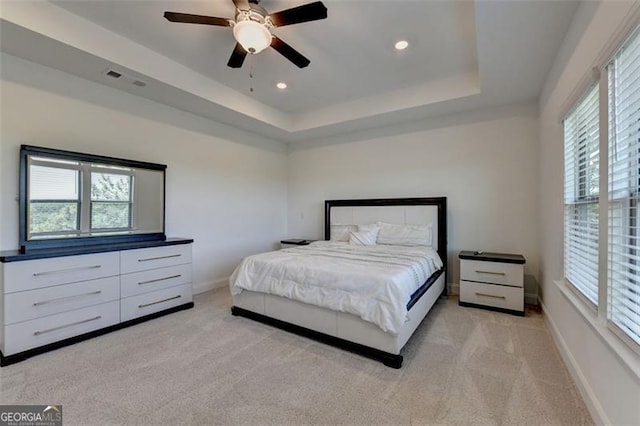 carpeted bedroom featuring ceiling fan and a raised ceiling