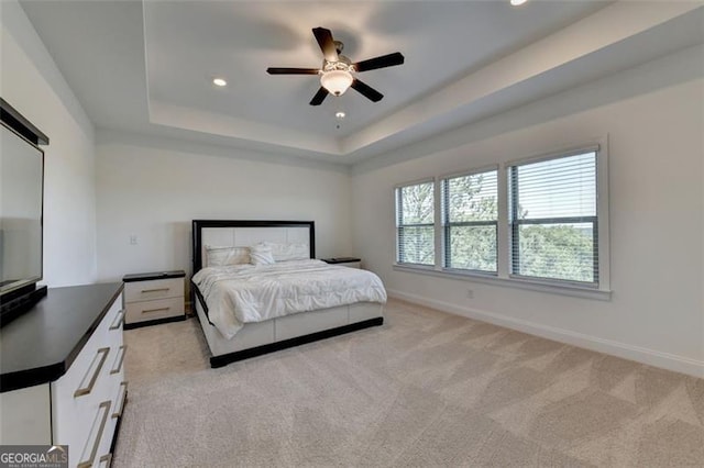 bedroom with ceiling fan, a raised ceiling, and light carpet