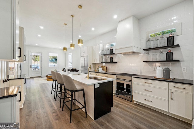 kitchen featuring premium range hood, open shelves, dark wood-type flooring, dark countertops, and tasteful backsplash