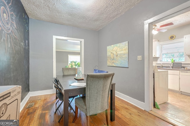 dining space featuring ceiling fan, a textured ceiling, and light hardwood / wood-style flooring