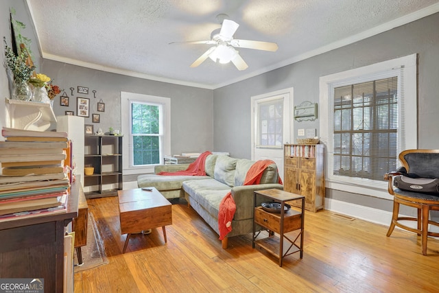 living room featuring ornamental molding, a textured ceiling, light wood-type flooring, and ceiling fan