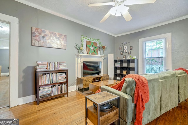 living room with hardwood / wood-style floors, crown molding, a textured ceiling, and ceiling fan