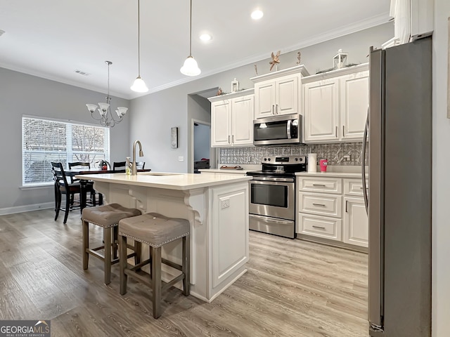 kitchen featuring sink, hanging light fixtures, an island with sink, stainless steel appliances, and backsplash