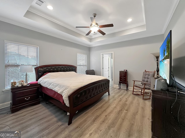 bedroom with a tray ceiling, ornamental molding, light hardwood / wood-style floors, and ceiling fan