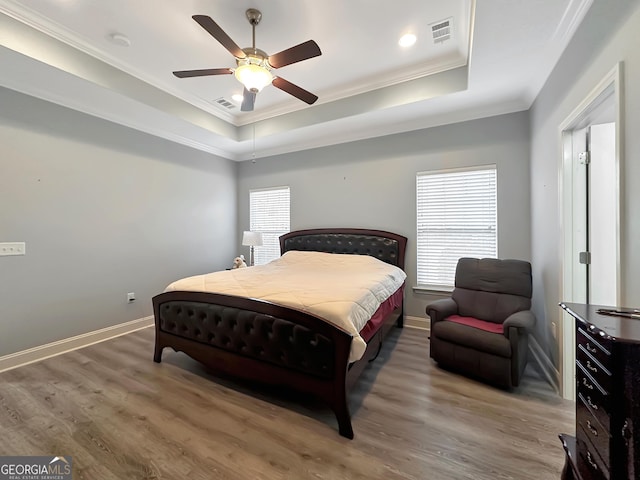 bedroom featuring a raised ceiling, dark hardwood / wood-style flooring, ornamental molding, and ceiling fan