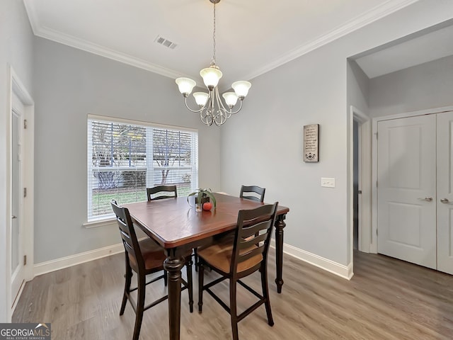 dining area featuring wood-type flooring, a notable chandelier, and crown molding