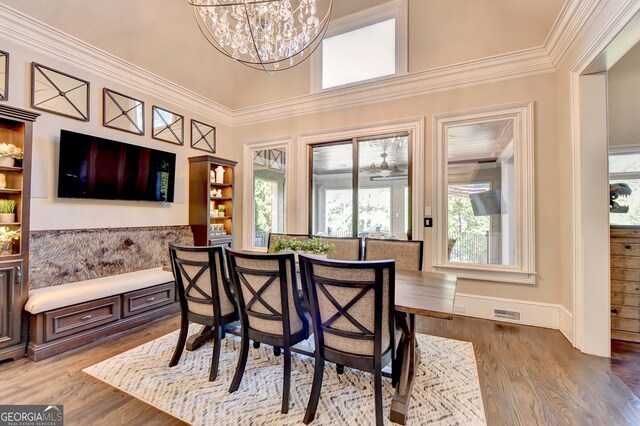 dining space featuring crown molding, light hardwood / wood-style flooring, and a chandelier