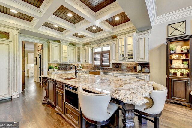 kitchen with a spacious island, hardwood / wood-style floors, and light stone counters