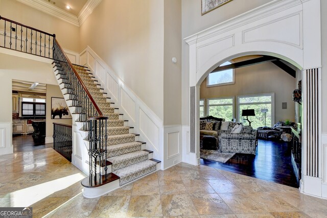 entrance foyer featuring crown molding, light hardwood / wood-style flooring, and a towering ceiling