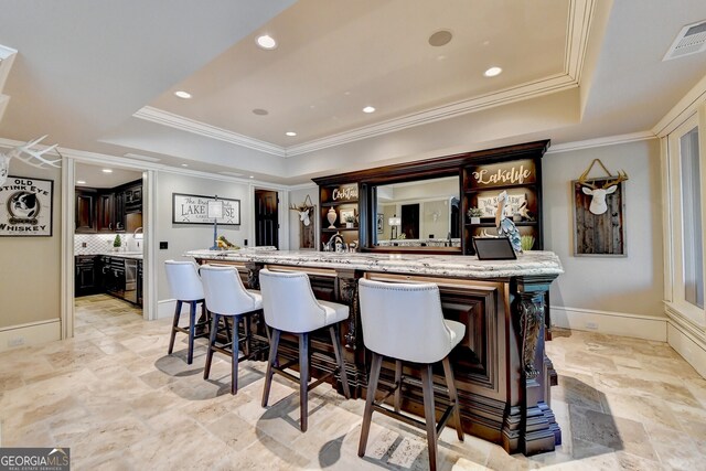 bar with decorative backsplash, light stone counters, crown molding, and a raised ceiling