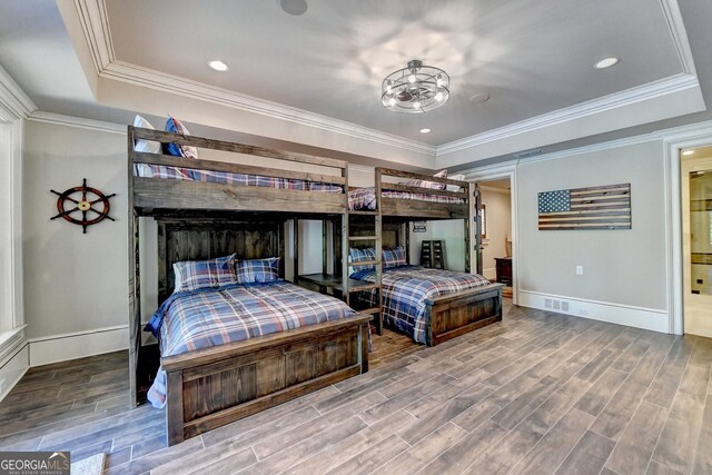 bedroom with crown molding, hardwood / wood-style flooring, and a tray ceiling