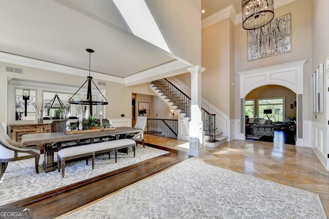 dining area with hardwood / wood-style floors, ornate columns, a high ceiling, crown molding, and a chandelier