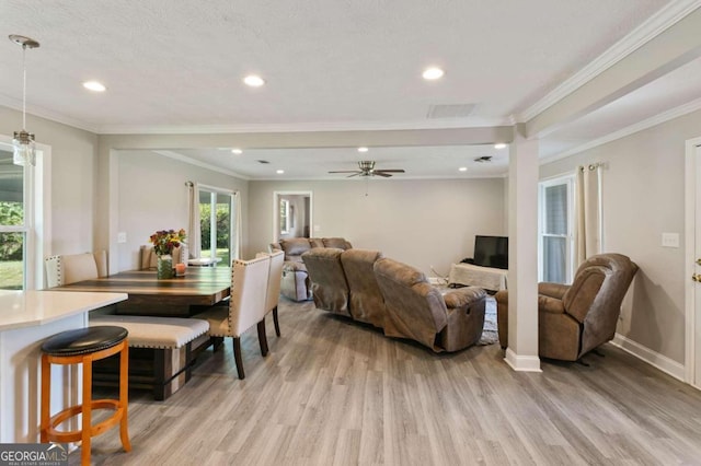 living room featuring ornamental molding, a textured ceiling, light wood-type flooring, and ceiling fan