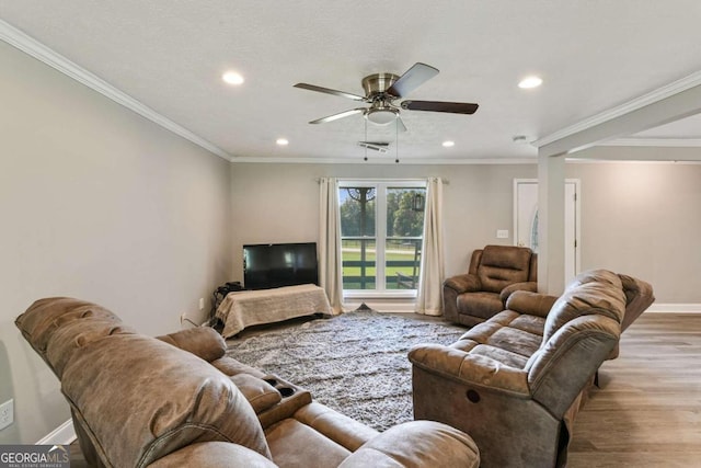 living room with ceiling fan, a textured ceiling, ornamental molding, and light hardwood / wood-style flooring