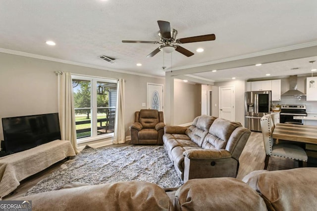 living room featuring ornamental molding, a textured ceiling, light hardwood / wood-style floors, and ceiling fan