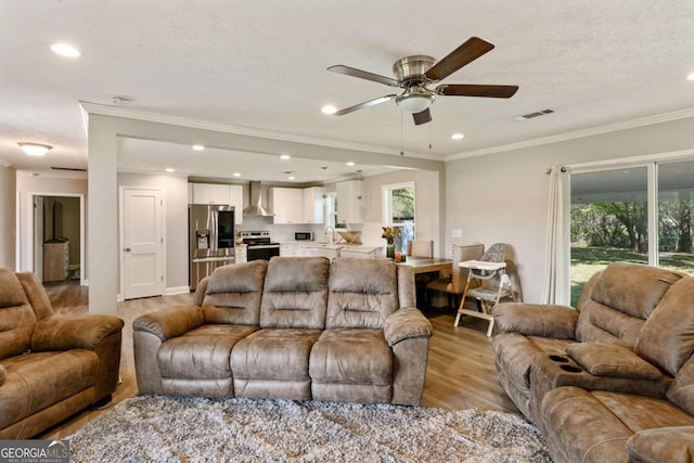 living room featuring ceiling fan, ornamental molding, light hardwood / wood-style flooring, and plenty of natural light