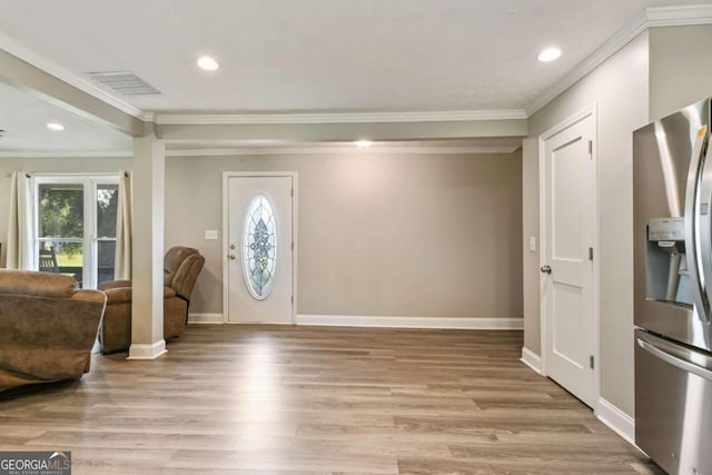 foyer entrance with light hardwood / wood-style floors and crown molding