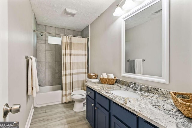 full bathroom featuring toilet, shower / bath combination with curtain, hardwood / wood-style floors, vanity, and a textured ceiling