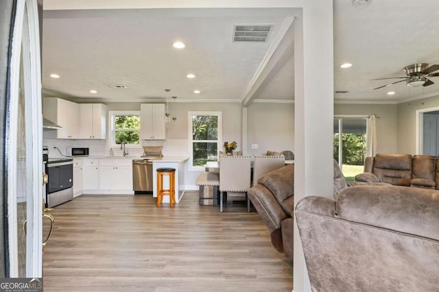 kitchen with white cabinetry, light wood-type flooring, sink, decorative light fixtures, and stainless steel appliances