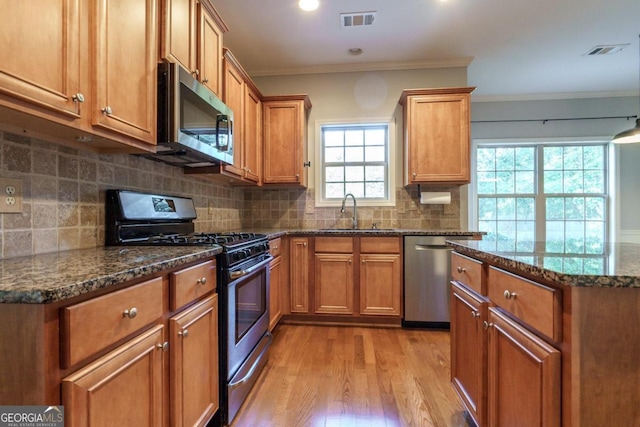 kitchen with sink, appliances with stainless steel finishes, light wood-type flooring, and plenty of natural light