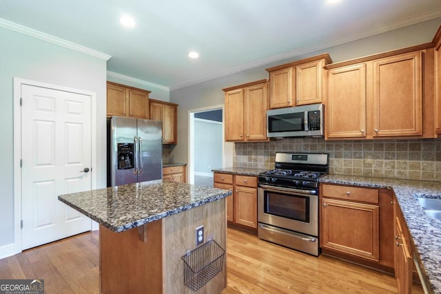 kitchen with dark stone countertops, light hardwood / wood-style floors, stainless steel appliances, and decorative backsplash